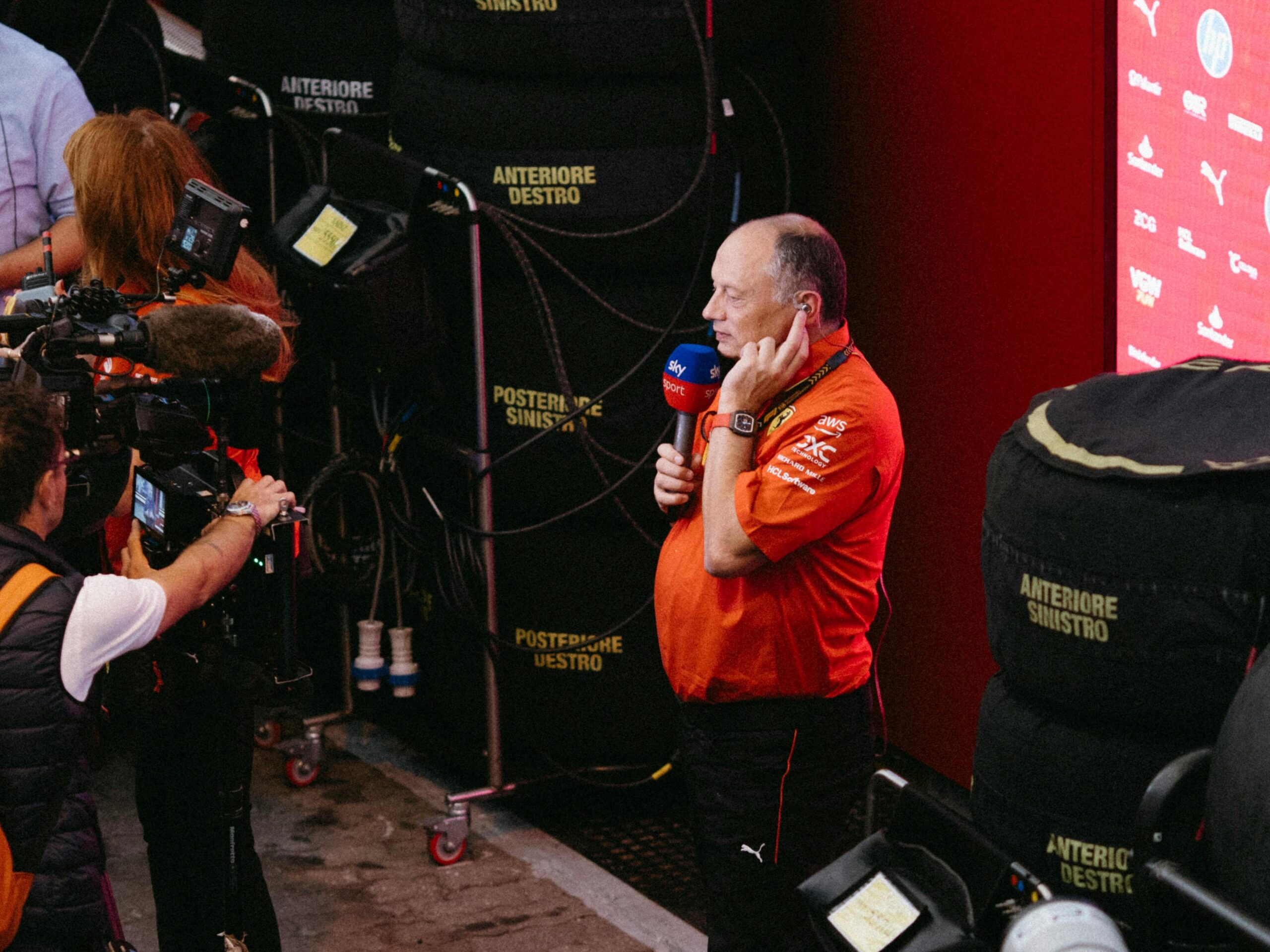 Racing team member interviewed during lively event atmosphere.